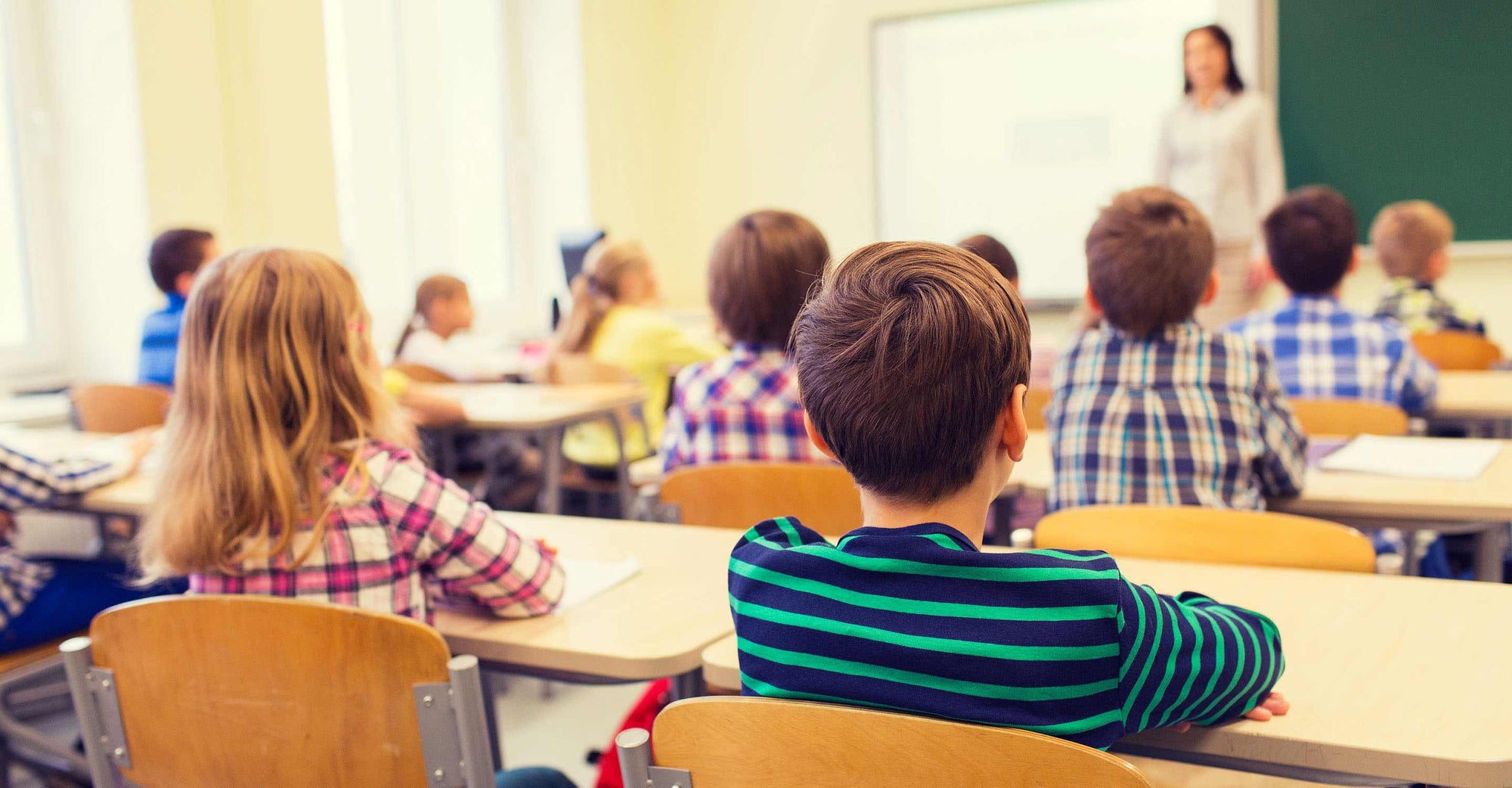Children sitting in a classroom, looking attentive and facing forward.