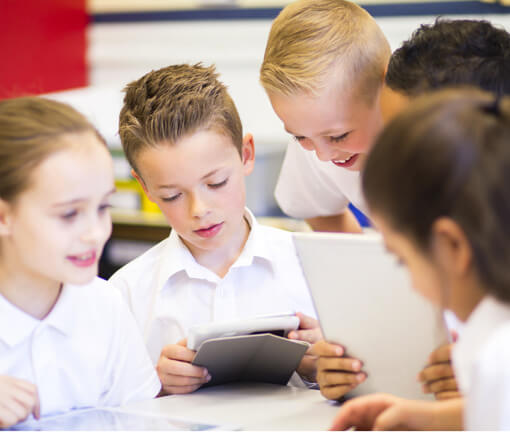 Kid on ipad surrounded by curious classmates