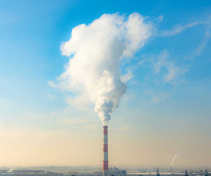 Smoke stack with smoke going in to sky